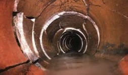View inside a cracked and damaged sewer pipe with water running along the bottom and visible structural deterioration on the pipe walls—ideal for those seeking sewer repairs in Bergen County NJ.